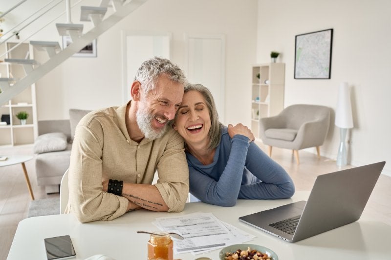 A man and woman on a laptop laughing